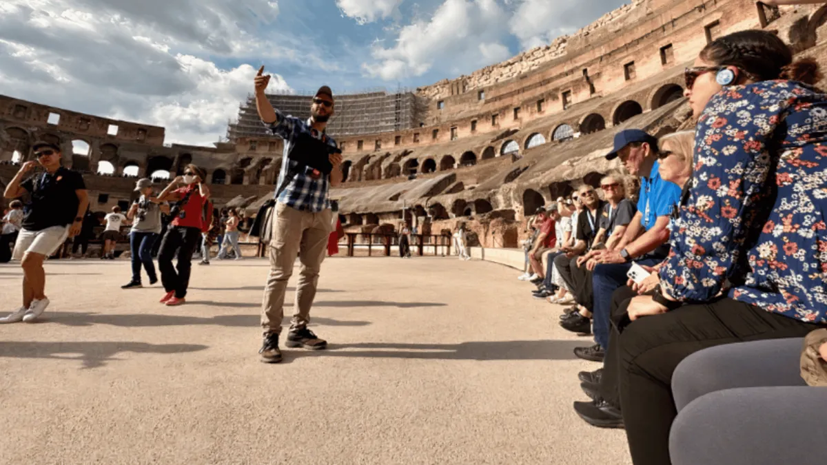 Small group climbing to the second tier of the Colosseum with the arena floor and hypogeum below on a Rome tour