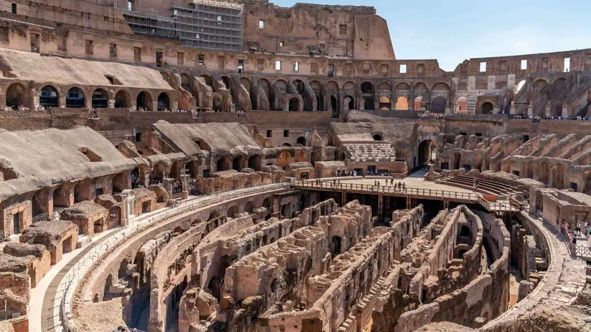 Visitors looking down into the excavated hypogeum from the Colosseum arena floor on an underground tour in Rome